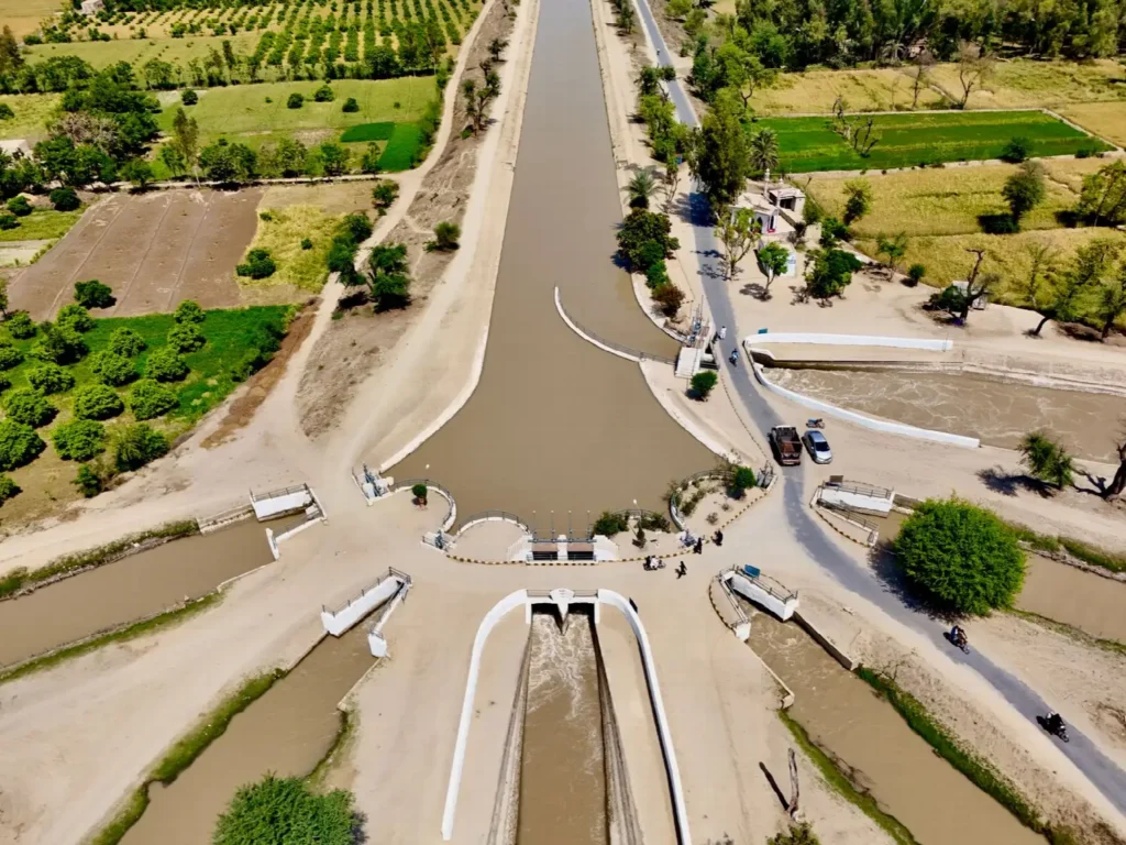 Aerial view of an irrigation canal splitting into channels through green farmland.